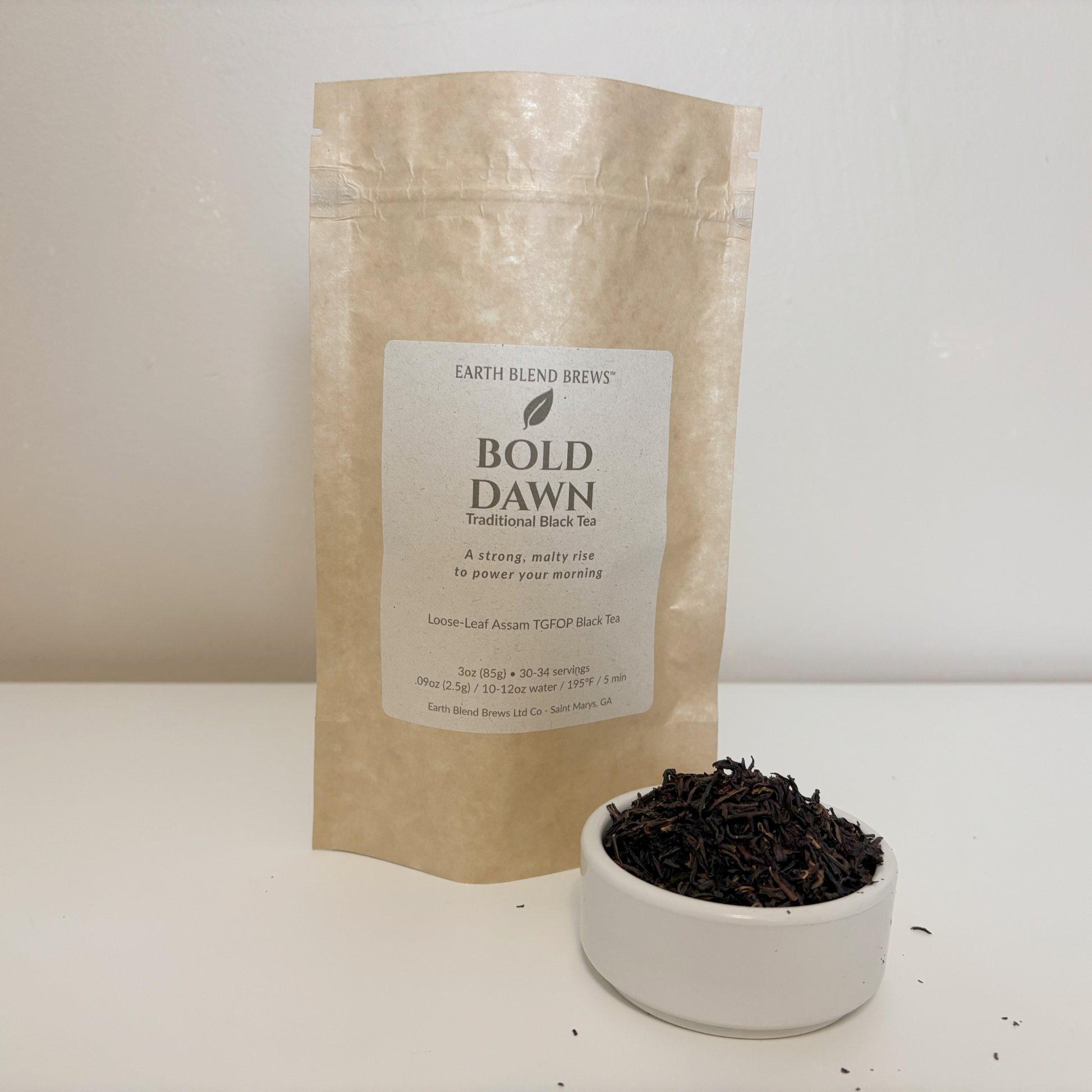 Tea package labeled 'Bold Dawn' from Earth Blend Brews with a bowl of black tea leaves on a white background.