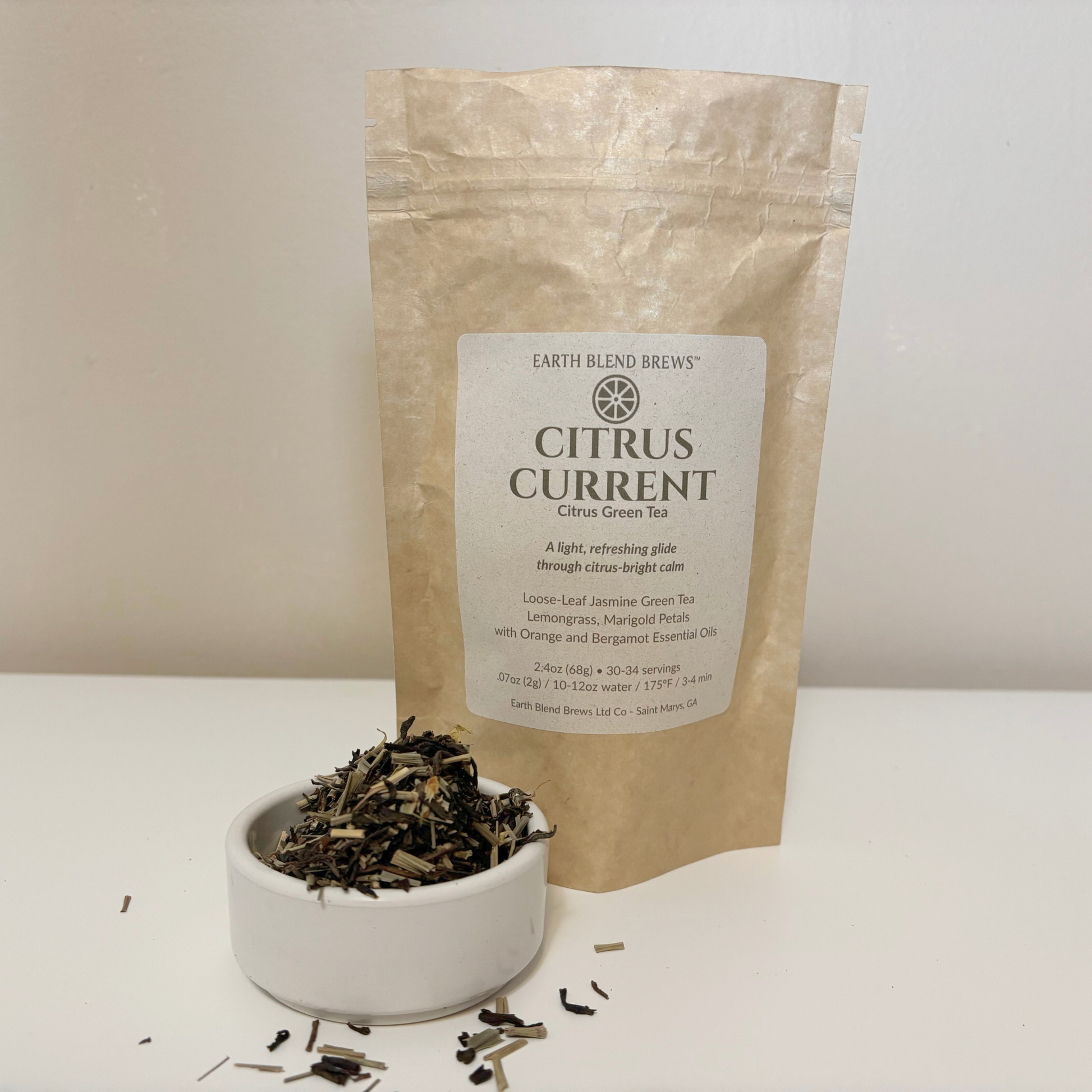 Bag of Earth Blend Brews Citrus Current tea with a bowl of tea leaves on a white surface.