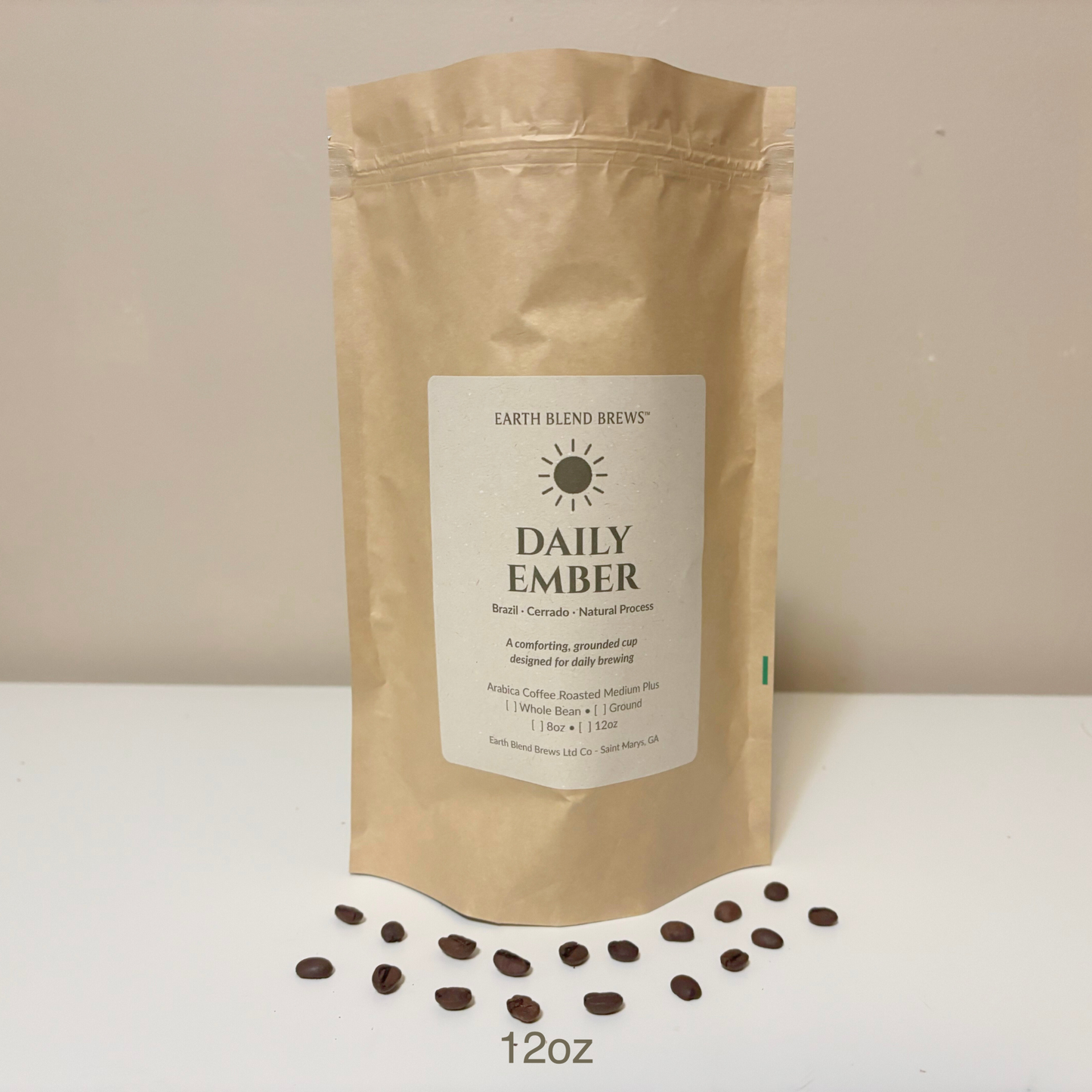 12oz Kraft paper coffee bag labeled 'Daily Ember' with scattered coffee beans on a light background