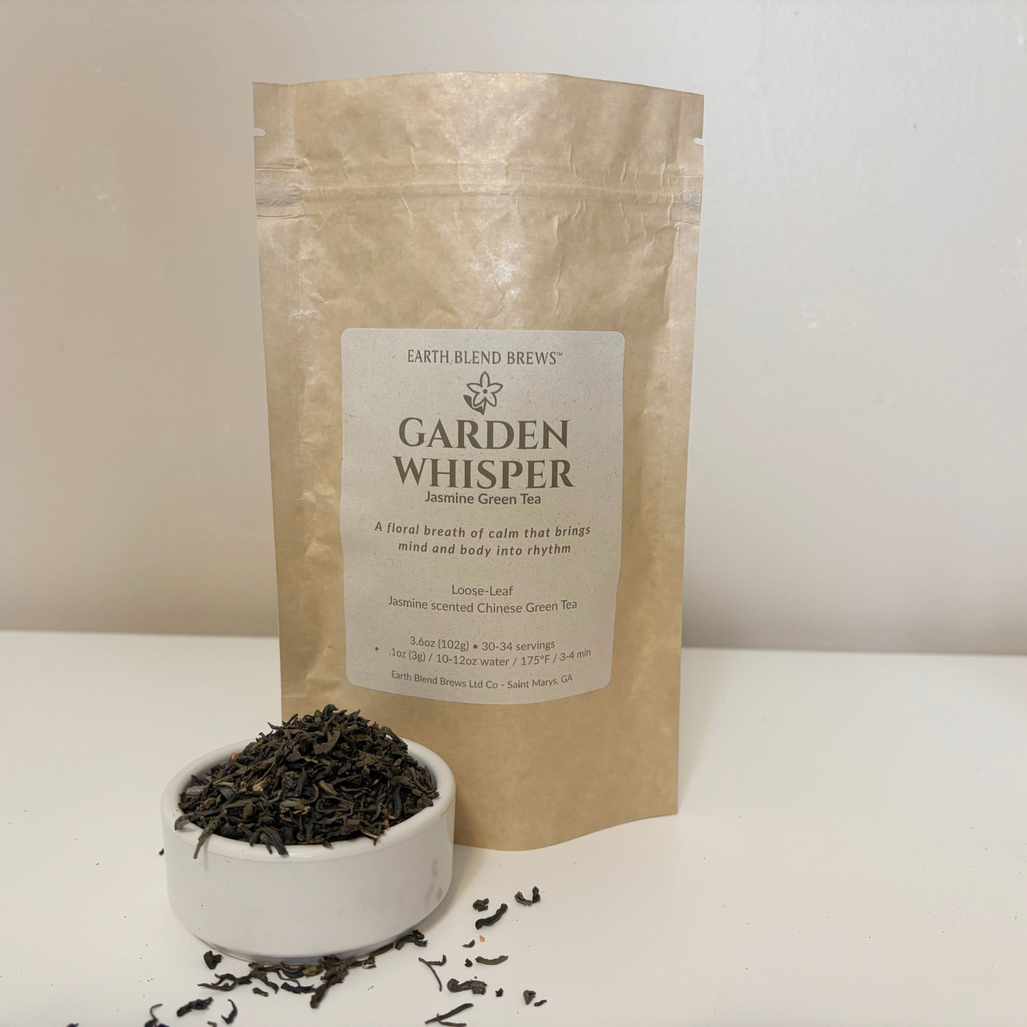 Tea packaging labeled 'Garden Whisper' with loose tea leaves in a bowl on a white background